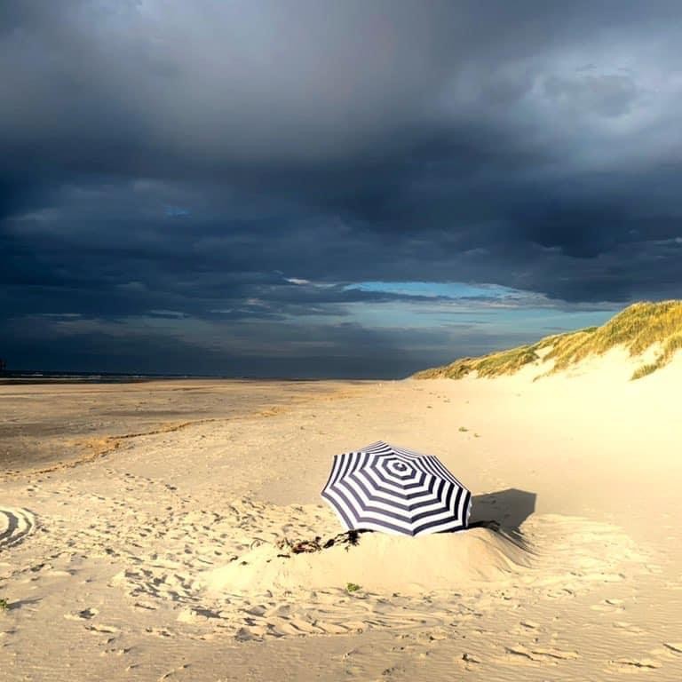 Paraplu op het strand Naar het strand op Ameland om te zonnen, wandelen, vliegeren of paardrijden. In de duinen op Ameland bij de zee.